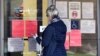 FILE - A woman checks job application information in front of IDES(Illinois Department of Employment Security)/WorkNet center in Arlington Heights, Ill., April 9, 2020.