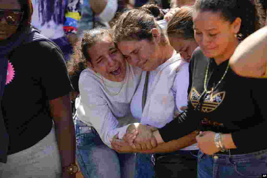 A sister of miner Santiago Mora, left, cries with other relatives as he is buried at the cemetery in La Paragua, Bolivar state, Venezuela. The collapse of an illegally operated open-pit gold mine in central Venezuela killed at least 14 people and injured several more, state authorities said, as some other officials reported an undetermined number of people could be trapped.