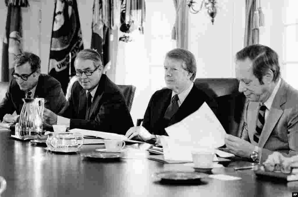 22 января 1977 года. Первый день Картера в Белом доме; рядом с президентом (слева направо) — глава Пентагона Гарольд Браун, госсекретарь Сайрус Вэнс и руководитель Минфина Майкл Блюменталь. Одним из первых шагов Картера на посту президента стало помилование уклонистов от призыва во время войны во Вьетнаме.