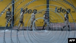 Indian paramilitary and police patrol near a barbed wire fence during a curfew imposed on the Kashmiri summer capital in Srinagar on July 19, 2013.