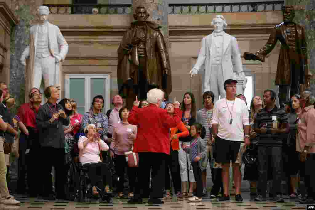 A Capitol Guide Service employee leads a group of tourists through Statuary Hall at the U.S. Capitol in Washington, D.C. Members of the Capitol Guide Service are not considered "essential" employees and tours will halt upon a federal government shutdown if lawmakers do not pass a budget by midnight.