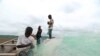 Here child slaves nervously prepare a fishing net under the watchful eye of a fisherman.