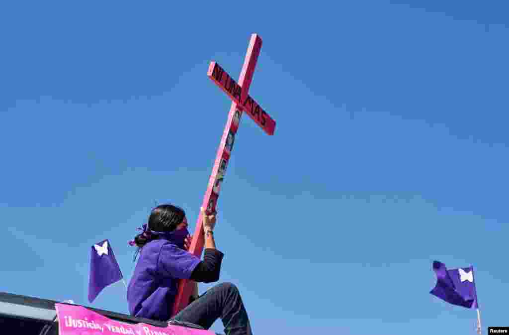 A mother seen atop a vehicle holding a cross with a sign reading "Not one more" during a caravan demanding an end to violence against women and femicide, ahead of a Women's Day protest, in Ciudad Juarez, Mexico, March 7 , 2021.
