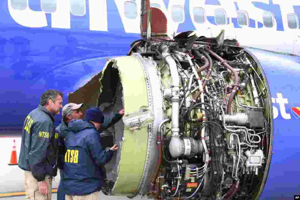 National Transportation Safety Board investigators examine damage to the engine of the Southwest Airlines plane that made an emergency landing at Philadelphia International Airport in Philadelphia, April 17, 2018. An "uncontained" engine failure sent debris flying like shrapnel into the plane and it broke a window. Passengers desperately saved a woman from getting sucked out. She later died and seven others were injured.