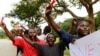 Roman Catholic priest Frank Bwalya (in red) and supporters hold red cards to display their displeasure with the government as they attend a rally in front of the National Assembly, in Lusaka, Zambia, March 22, 2011.