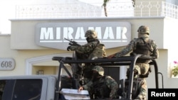 Military personnel stand atop a truck outside the Miramar building during a raid in Mazatlan, Feb. 22, 2014. 