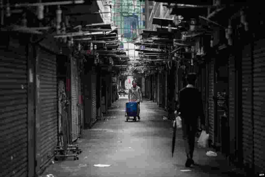 Seorang pria membawa kereta dorong di sebuah pasar jalanan di Hong Kong.