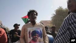 Muandamanaji wa Sudan akiwa ameshikilia bango lenye picha ya muandamanaji anayedaiwa kuuawa na vikosi vya usalama lililoandikwa 'Hakuna ushirikiano, Hakuna usawa.
