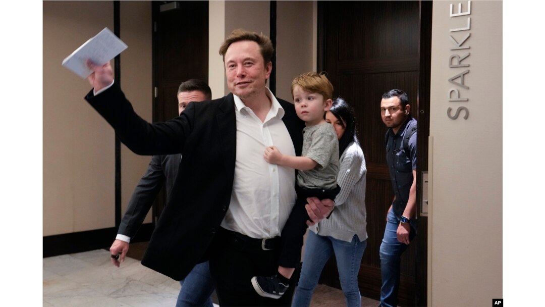 Twitter CEO Elon Musk waves as he leaves carrying his child after speaking at the POSSIBLE marketing conference, Tuesday, April 18, 2023, in Miami Beach, Fla. (AP Photo/Rebecca Blackwell)