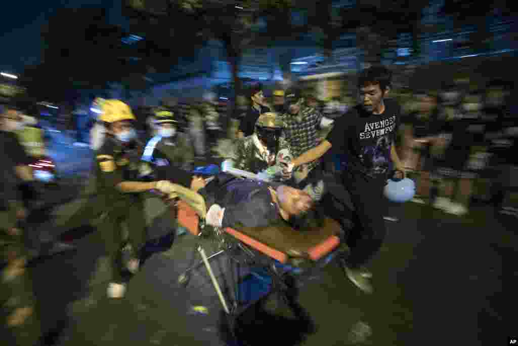Pro-democracy protesters help to move a protester with gun-shot injuries during an anti-government rally outside the Parliament in Bangkok, Thailand.