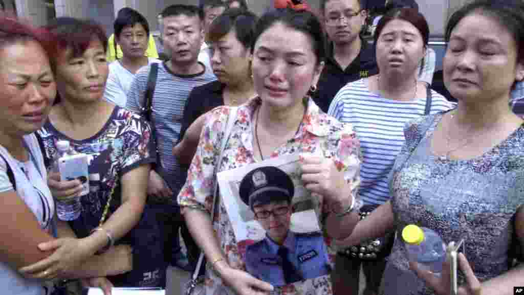 Ảnh chụp từ đoạn video của AP cho thấy một phụ nữ cầm hình của con trai là nhân viên cứu hỏa bị mất tích bên ngoài một khách sạn nơi các quan chức tổ chức họp báo tại Thiên Tân, ngày 16/8/2015. Trong số thương vong có nhóm đầu tiên gồm hơn 30 nhân viên cứu hỏa, một chục người đã ùa vội vào để dập tắt một đám cháy. Nhiều người nay đã chết hay mất tích. 