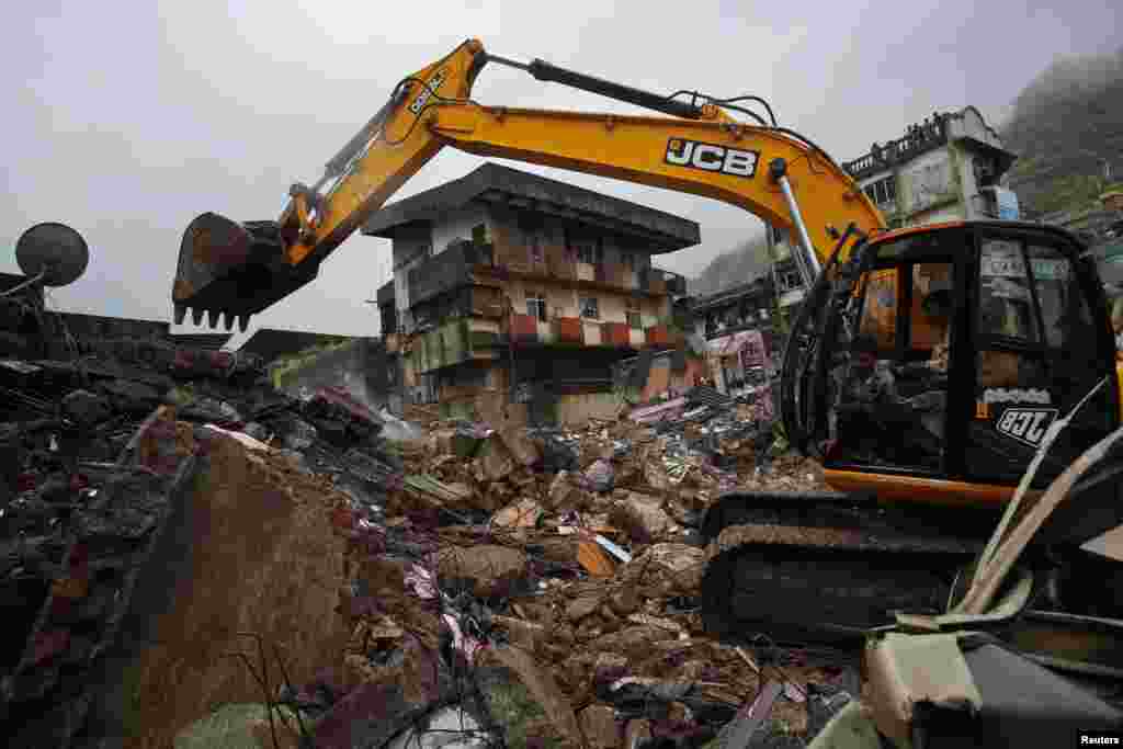 Rescue workers use an excavator to scour through the debris of a collapsed residential building on the outskirts of Mumbai, India, June 21, 2013.