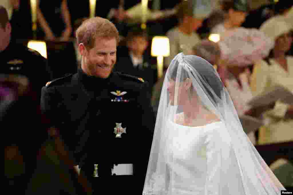 Principe Harry olha para a sua noiva Meghan Markle no momento em que ela chega acompanhada do Príncipe de Gales à capela de S. George, no Castelo de Windsor. 19 de Maio 2018