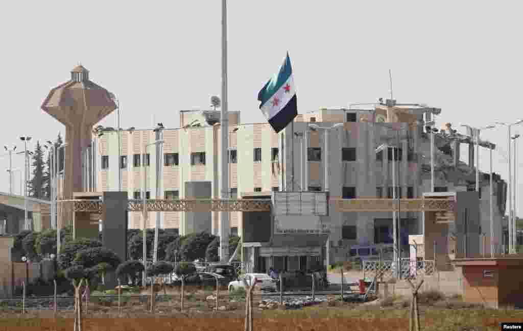 A Syrian independence flag and the damaged customs office at Syria's Tel Abyad border gate are pictured from the Turkish town of Akcakale, October 5, 2012.