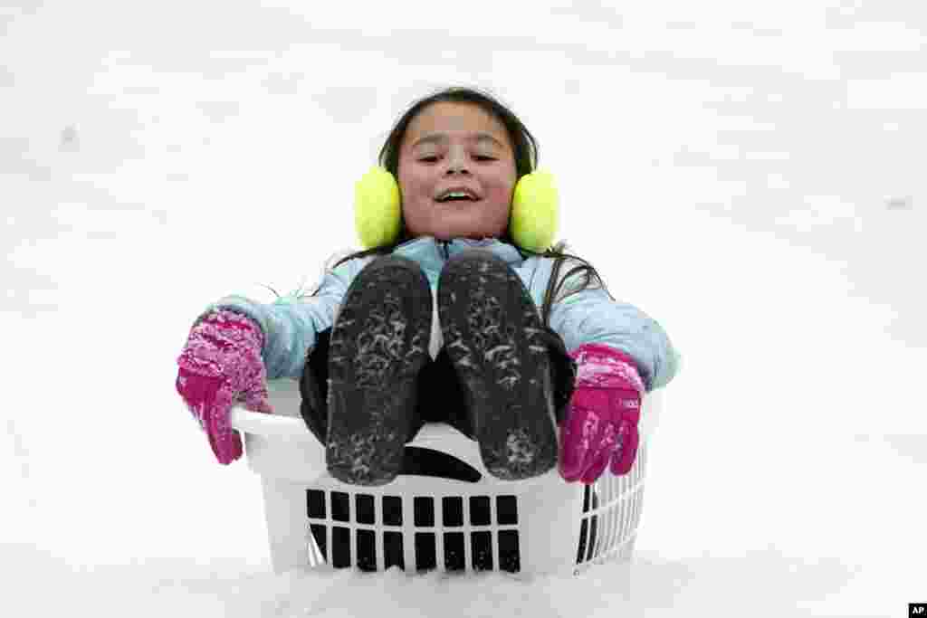Peyton McKinney uses a laundry basket for a sled in Nolensville, Tennessee, Feb. 15, 2021. Much of Tennessee was hit with a winter storm that brought freezing rain, snow, sleet and freezing temperatures.