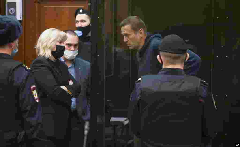 In this handout photo provided by Moscow City Court, opposition leader Alexei Navalny talks to his lawyers during a hearing to a motion from the Russian prison service to convert his suspended sentence from the 2014 criminal conviction into a real prison term in the Moscow City Court. 