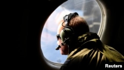 Un tripulante observa el mar a través de la ventanilla de un avion P3 Orion de la Fuerza Aérea de Nueva Zelandia.