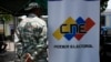 Un miembro de la milicia se detiene al lado de un banner del Consejo Nacional Electoral (CNE) en un punto de inscripción en el Registro Electoral. Archivo (AP Photo/Ariana Cubillos)