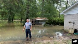 Miguel Flores se encuentra en su patio trasero inundado afuera de su casa en el vecindario de Kingwood, en el noreste de Houston, Texas, EEUU, el sábado 4 de mayo de 2024. (Foto AP/Juan Lozano)