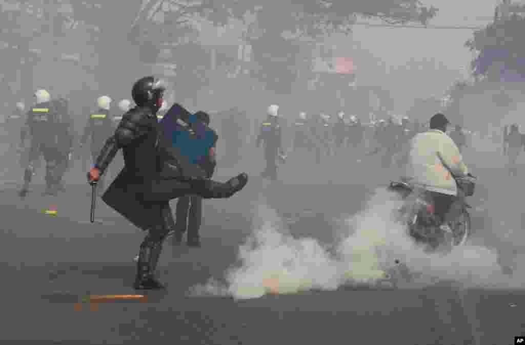 Seorang polisi anti huru hara menghindari granat gas ketika polisi menembakkannya untuk membubarkan demonstran di , 27 Januari 2014.