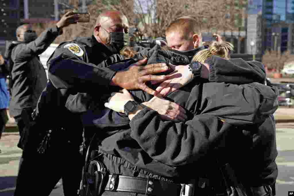 Nashville Police Chief John Drake, left, and a group of police officers embrace after speaking at a news conference, Dec. 27, 2020, in Nashville, Tennessee. The officers are credited with evacuating people before an explosion took place in downtown Nashville early Christmas morning. 