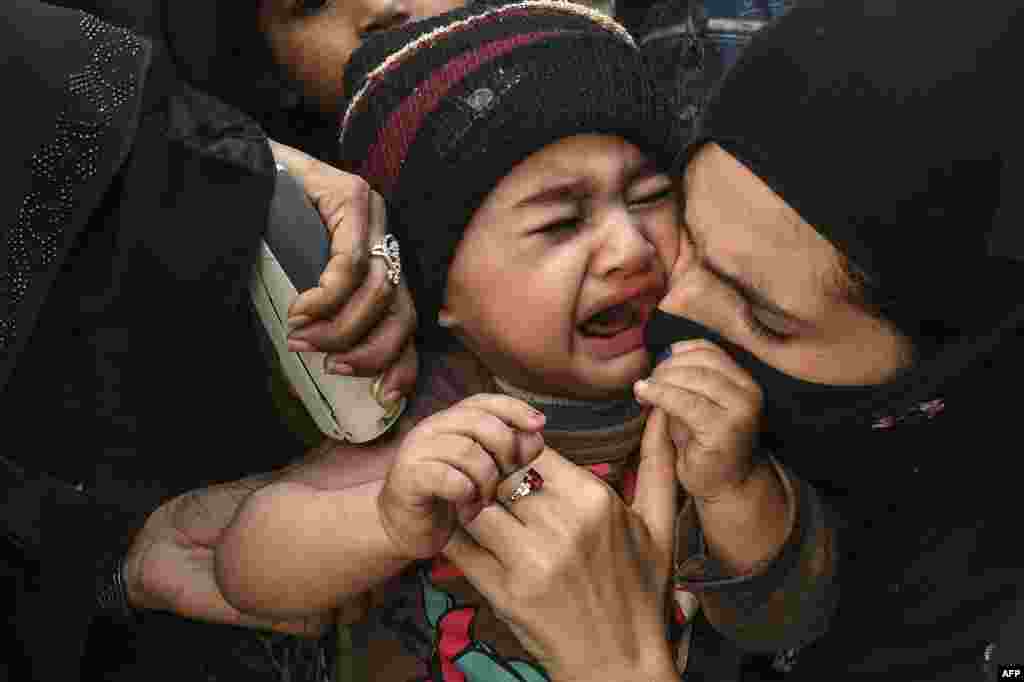 A child reacts as a health worker administers an Inactivated polio vaccine (IPV) during a polio vaccination campaign in Lahore, Pakistan.