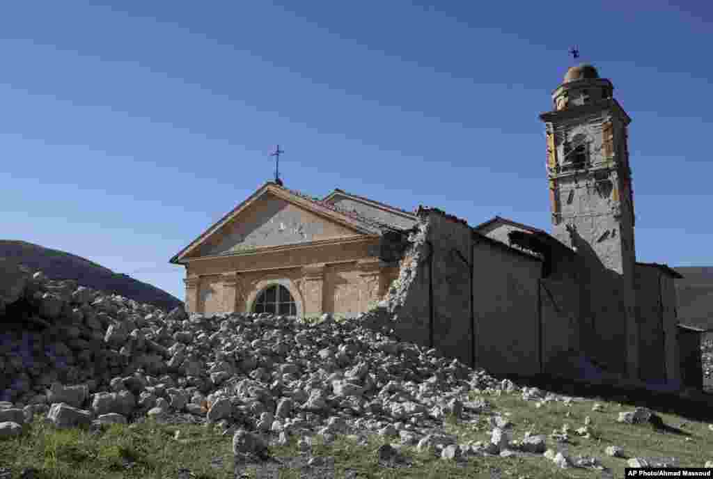 Menara Gereja Madonna degli Angeli masih kokoh berdiri di tengah puing-puing bangunan yang hancur akibat gempa di dekat Norcia, Italia tengah (30/10). (AP/Gregorio Borgia)