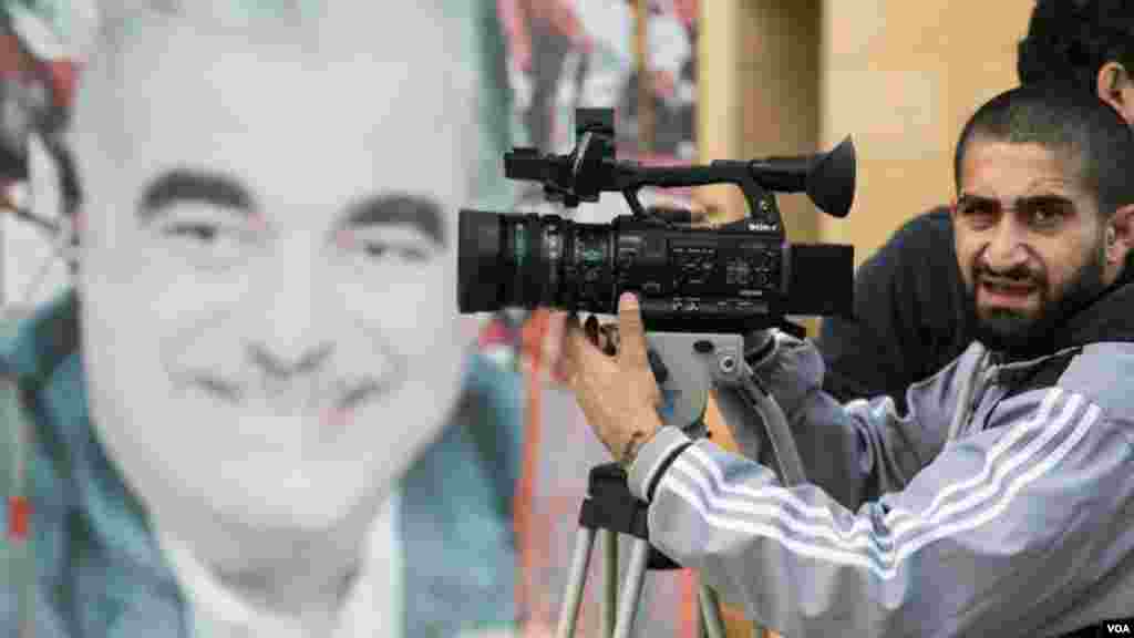 A photographer takes pictures during a parade marking Independence Day, Beirut, Lebanon, Nov. 22, 2017. In the background is a photo of Prime Minister Saad Hariri's father, Rafik, who was killed in a car bomb in 2005. He was previously prime minister. (John Owens for VOA)
