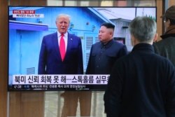 People watch a TV screen showing a file image of North Korean leader Kim Jong Un and U.S. President Donald Trump, left, during a news program at the Seoul Railway Station in Seoul, South Korea, Dec. 31, 2019.