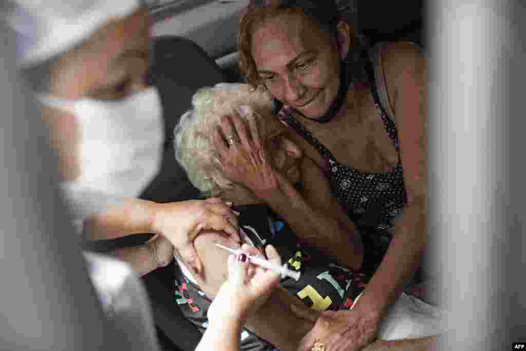 An elderly woman gets a shot of China's Sinovac CoronaVac vaccine as part of a priority COVID-19 vaccination program for the elderly at a drive-thru vaccination center in Rio de Janeiro, Brazil.