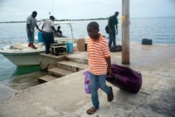 A child evacuated from a nearby cay because of the danger of floods drags his suitcase when he arrives on a ship at the port before the arrival of Hurricane Dorian in Sweeting's Cay, Grand Bahama, Bahamas, Aug. 31, 2019.