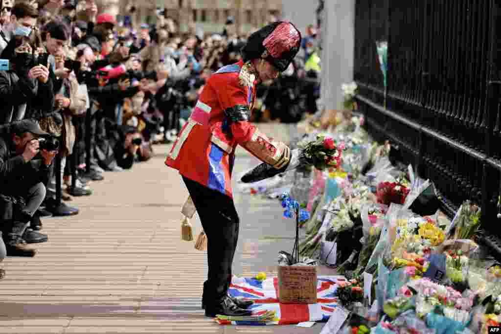 An ardent Royals fan lays a floral tribute at the front of Buckingham Palace in central London, after the announcement of the death of Britain's Prince Philip, Duke of Edinburgh.