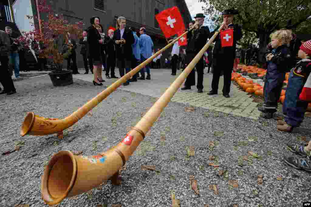 Presiden Finlandia Sauli Niinistoe (kedua dari kiri) dan istrinya Jenni Haukio (kiri) melihat dua pria meniup terompet tradisional Swiss, selama kunjungan ke sebuah peternakan di kota Seegraben, Swiss.