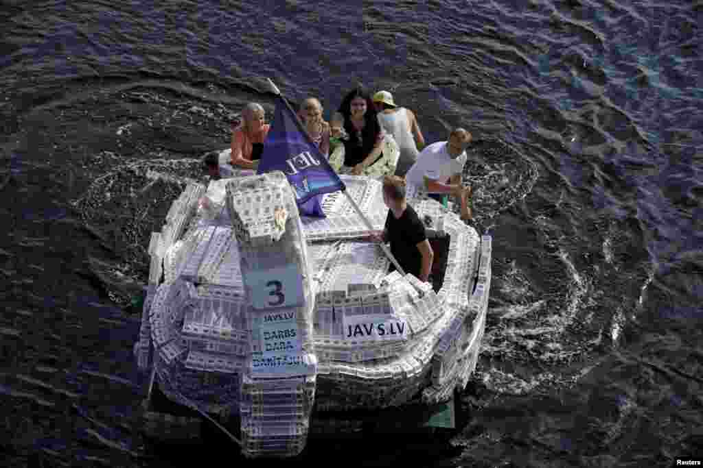 People navigate along the Lielupe river as they participate in the Milk Carton Boat Race in Jelgava, Latvia, Aug. 27, 2016.