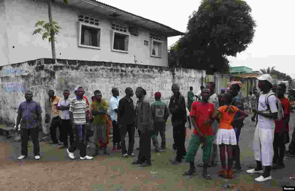 Residents gather to watch security forces patrol the street near state television headquarters in Kinshasa, Dec. 30, 2013.