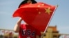 一名站在北京天安门广场的小男孩身穿美国T恤手拿中国国旗。（2019年5月7日）