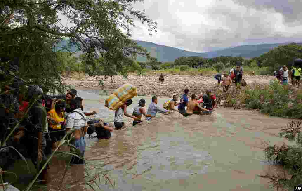Migrants use a rope to cross the Tachira River, the natural border between Colombia and Venezuela, as the official border remains closed due to the COVID-19 pandemic in Cucuta, Colombia, Nov. 19, 2020.
