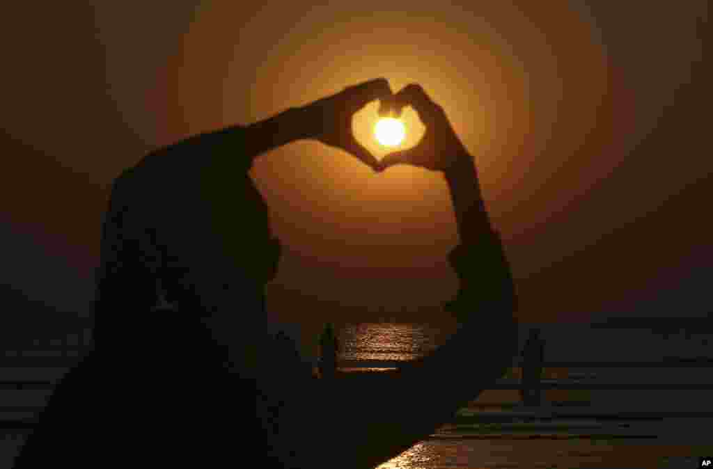 A boy make heart sign while the last sunset of 2020 hangs over the Sindh's provincial capital of Karachi, Pakistan.