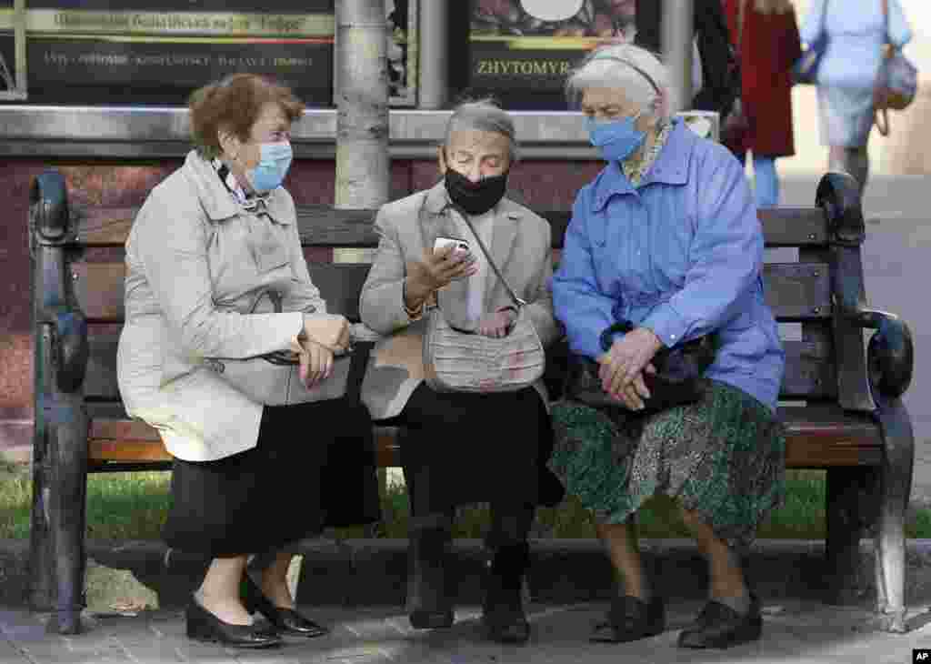 Elderly women look at a phone on a bench in capital Kyiv's main Khreshchatyk Street, Ukraine.