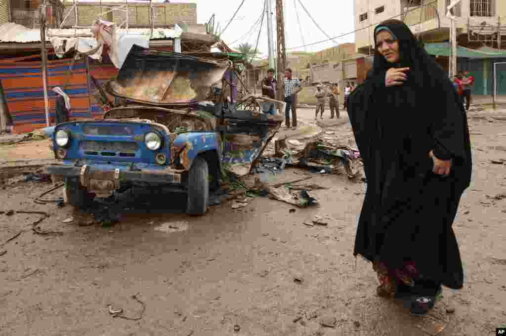 An Iraqi woman passes by the scene of a car bomb attack in Kamaliyah, a predominantly Shi'ite area of eastern Baghdad, May 20, 2013.