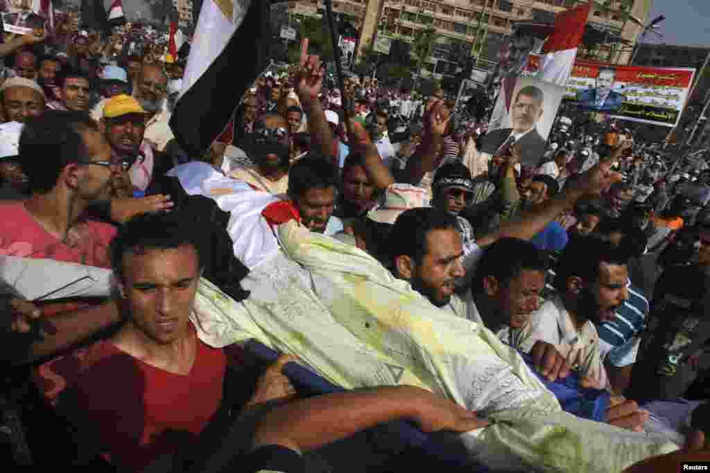 Những người ủng hộ tổng thống bị lật đổ Mohamed Morsi mang thi thể của một người ủng hộ thiệt mạng vì bạo lực đến bên ngoài trụ sở Vệ binh Cộng hòa ở Cairo, 8 tháng 7, 2013.