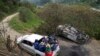 ARCHIVO: Miembros de la Guardia Indígena pasan junto a un vehículo que quemaron después de un ataque de rebeldes del Estado Mayor Central (EMC), en Toribio, Colombia, el martes 19 de marzo de 2024. 