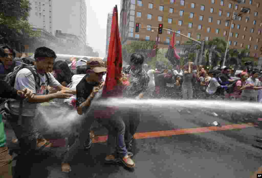 Polisi Filipina menyemprotkan air ke arah para demonstran yang berusaha mendekati komplek Kedutaan AS di Manila, Filipina untuk memprotes rencana kunjungan Presiden Obama. 
