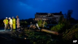Los trabajadores de servicios públicos examinan los daños de la tormenta a lo largo de Cothran Road, el miércoles 8 de mayo de 2024, en Columbia, Tennessee.
