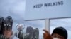 A worker urges pedestrians to keep walking outside an Olympic flame as part of a COVID-19 precautions during the 2020 Summer Olympics, Aug. 2, 2021, in Tokyo.