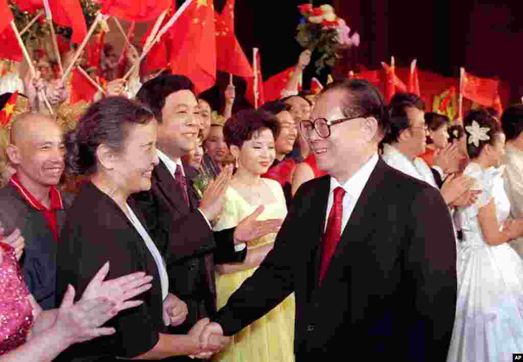 1999年9月28日,在北京的文艺演出“祖国颂”之后,中国主席江泽民和乐团指挥郑小英握手。其他在场者似乎有(左起)京剧演员孟广禄、播音员赵忠祥和歌唱家董文华。