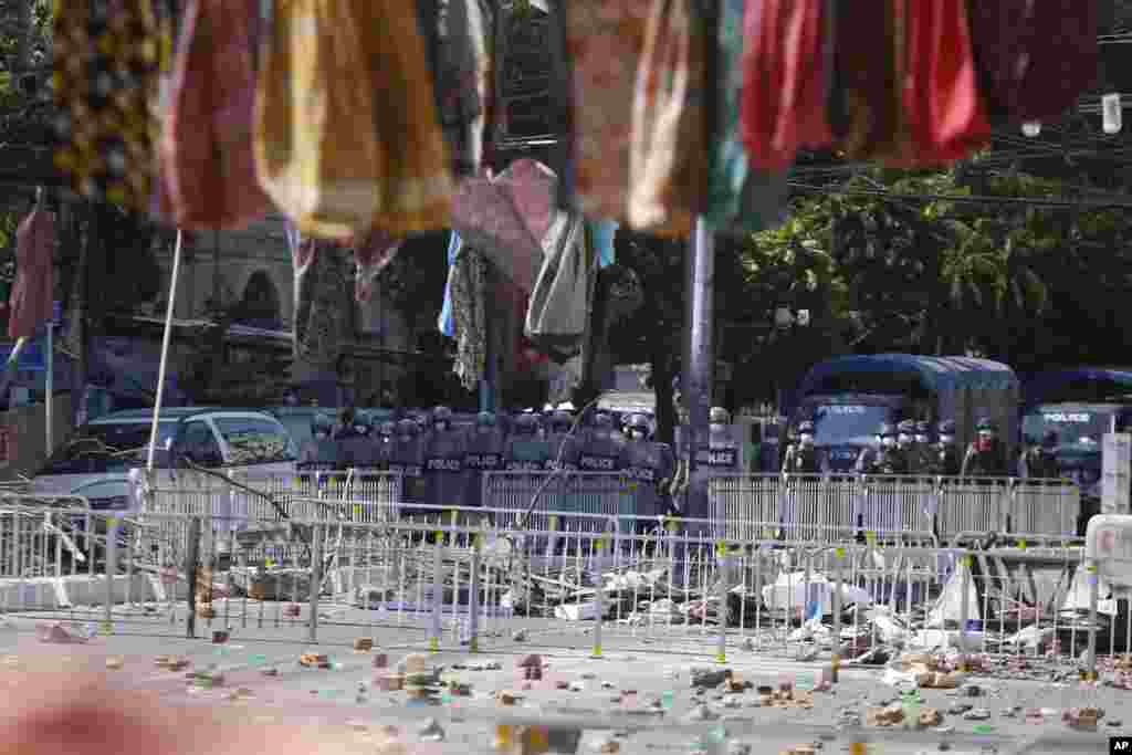 Myanmar riot police stand in front of road barricade, as protesters hang women's sarongs overhead in Yangon, Myanmar. There is a traditional belief that walking underneath women's sarongs (htamein) will bring bad luck especially to men.