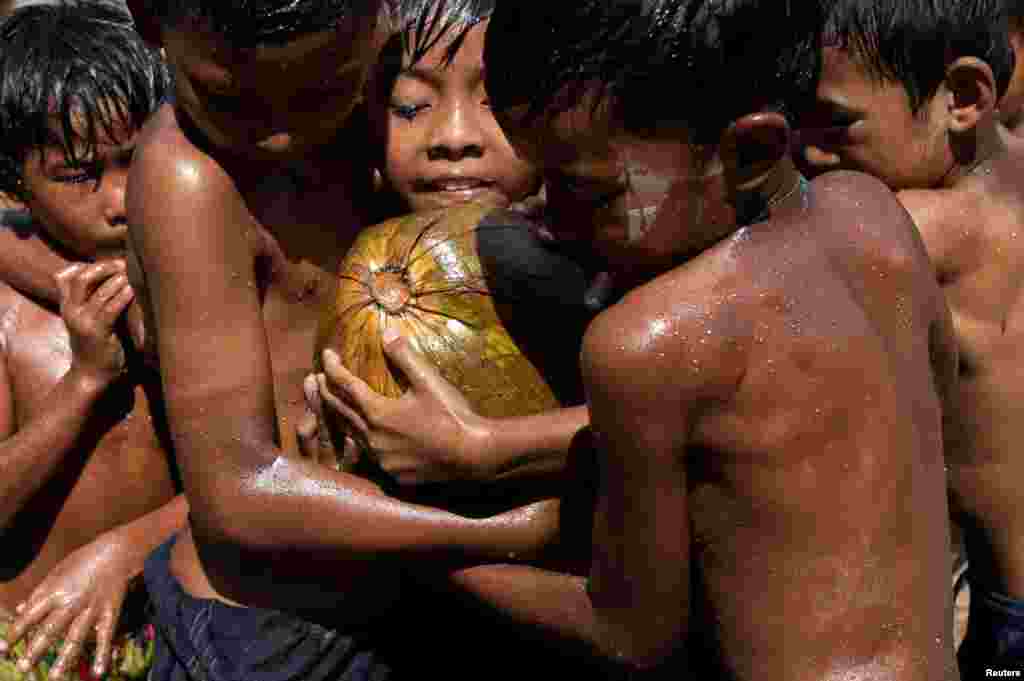 Children play with an oiled coconut during Myanmar's 73rd Independence Day celebrations amid the spread of the COVID-19 in Yangon.