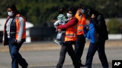 Un funcionario de inmigración guatemalteco lleva a un menor que fue deportado de Estados Unidos. 