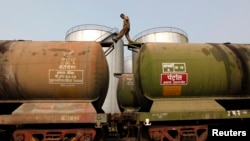 FILE - A worker walks atop a tanker wagon to check the freight level at an oil terminal on the outskirts of Kolkata, Nov. 27, 2013. 